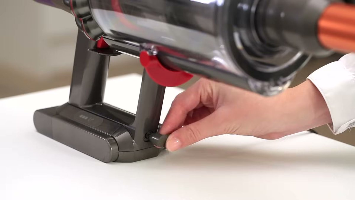 Close-up of Dyson V10 Absolute docking into its charging base with hand pressing release button